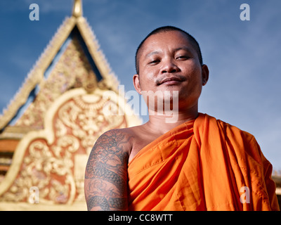 Mid adult Asian monk smiling at camera in buddhist monastery, Phnom Penh, Cambodia, Asia. Low angle Stock Photo