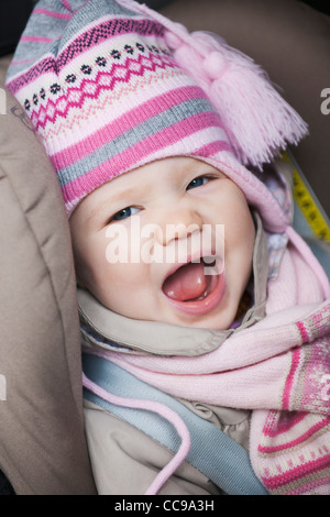 Close-up of Baby Girl Sitting in Car Seat wearing Winter Clothing Stock Photo