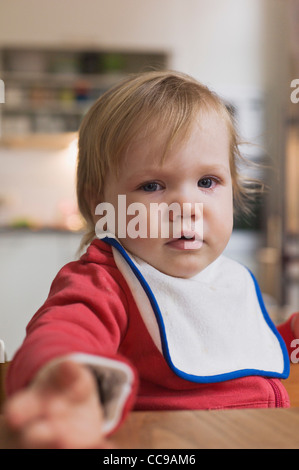 Portrait of Sad Baby Girl Sitting in High Chair Stock Photo
