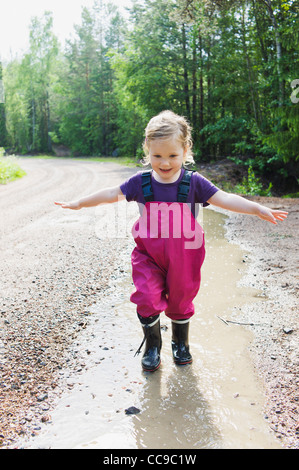 Young Girl Playing in Puddle, Sweden Stock Photo