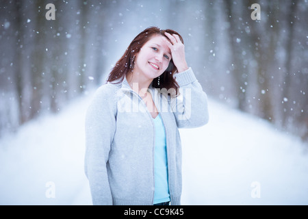 Enjoying the first snow: young woman outdoors on a lovely forest path watching the snowflakes falling (color toned image) Stock Photo