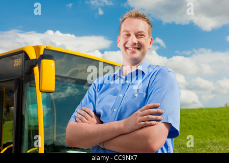 Bus driver is standing in front of his bus under al blue sky Stock Photo