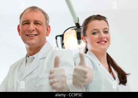 Dentists in their surgery looking at the viewer standing side by side Stock Photo