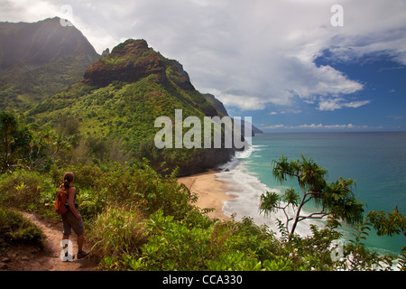 Hiker looks out to the Na Pali Coast from the Kalalau Trail near Hanakapi'ai Beach, Kauai, Hawaii. (Model Released) Stock Photo