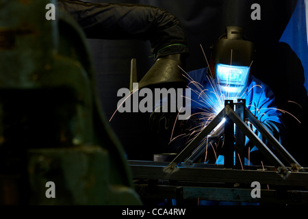 A welder welds metal in a manufacturing factory. Stock Photo