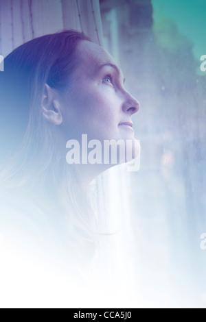 Woman looking up out of window Stock Photo