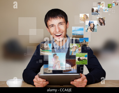 A technology man has images flying away from his modern tablet computer, He is at home. Designed poster for a communication, Stock Photo