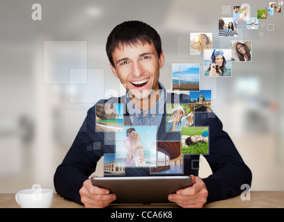 A technology man has images flying away from his modern tablet computer, He is at office. Designed poster for a communication, Stock Photo