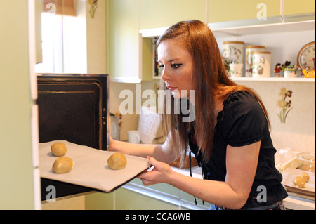Young woman 20s age group baking cakes in kitchen UK Stock Photo