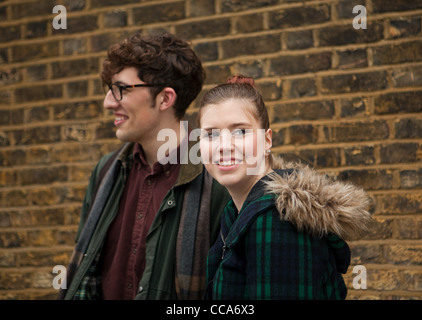 Young couple by brick wall, smiling Stock Photo
