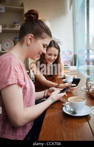 Young women in cafe using cell phones Stock Photo