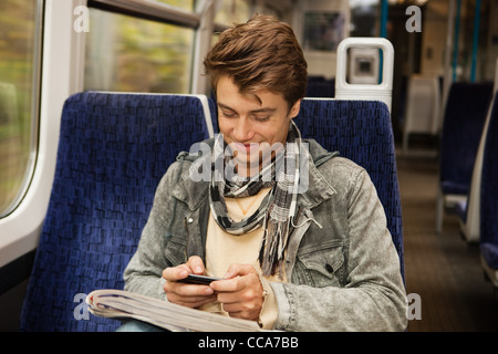 Young man travelling on train using cellphone Stock Photo