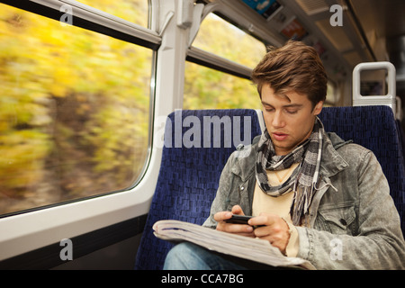 Young man travelling on train using cellphone Stock Photo