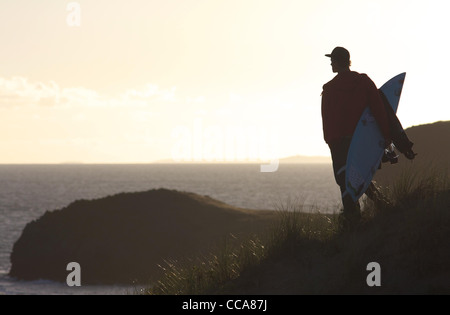 A surfer makes his way over sand dunes towards the beach in the late summer sun. Stock Photo