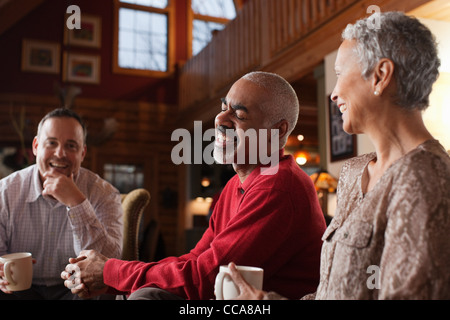 Mature friends laughing together in living room Stock Photo