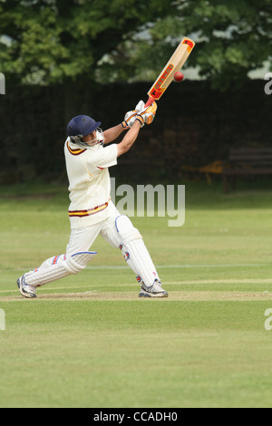 A cricketer in full protective clothing driving the ball towards the viewer. Stock Photo