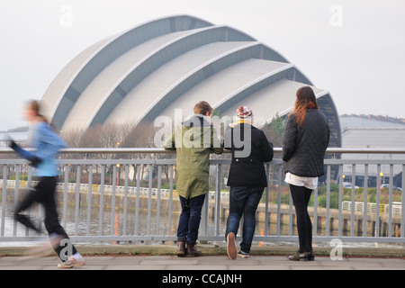 Three passers-by view the Clyde Auditorium (locally known as the Armadillo) from the Clyde Arc bridge in Glasgow, Scotland Stock Photo