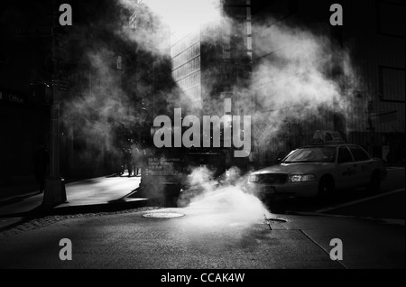 A taxi cab seen driving through a steam cloud by Columbus Circle subway stop on 59th Street in Manhattan, New York City, USA. Stock Photo