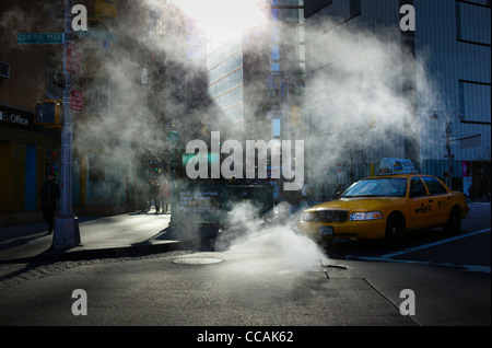 A taxi cab seen driving through a steam cloud by Columbus Circle subway stop on 59th Street in Manhattan, New York City, USA. Stock Photo