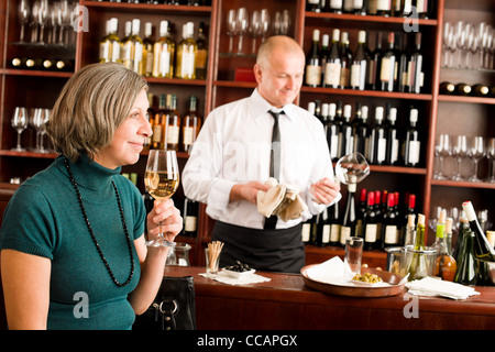 Wine bar senior woman enjoy wine glass in front of bartender Stock Photo