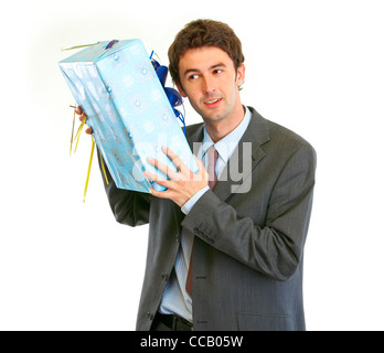Modern businessman shaking present box trying to guess what's inside Stock Photo