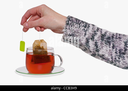 aus einer Tasse mit Tee wird der Teebeutel herausgezogen | the tea bag is pulled out of a cup with tea Stock Photo