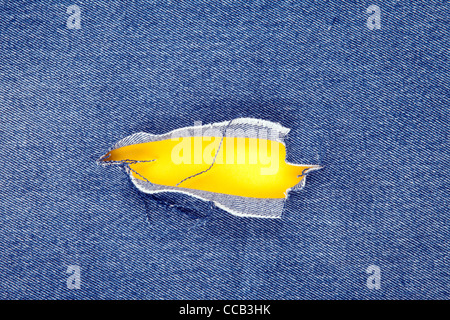 Hole in denim jeans with yellow background Stock Photo