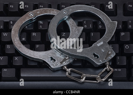 Handschellen liegen auf einer Computertastatur | handcuffs are on a computer keyboard Stock Photo