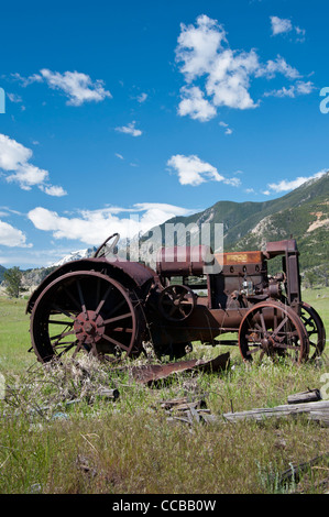 An antique tractors sits abandoned in a pasture in south central Montana. The Beartooth Mountains loom in the background. Stock Photo