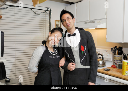 Asian couple with formal aprons standing in a kitchen. Stock Photo