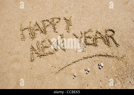 sentence happy new year written in the sand of a beach Stock Photo