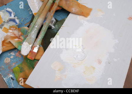 artist's stained palette, three brushes and paint tubes Stock Photo