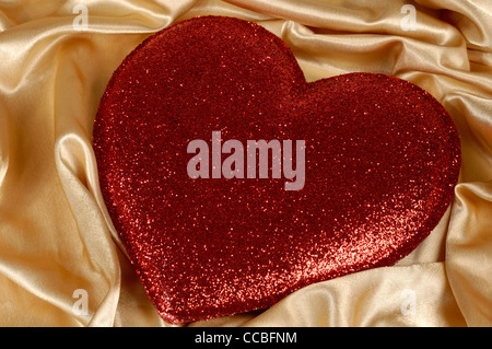 Red heart-shaped cushion on golden fabric background Stock Photo