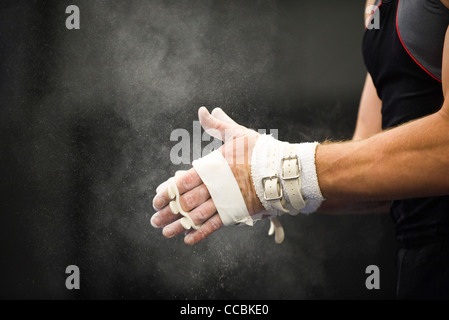 Gymnast applying chalk power to hands in preparation Stock Photo