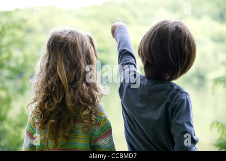 Children looking at lake as boy points