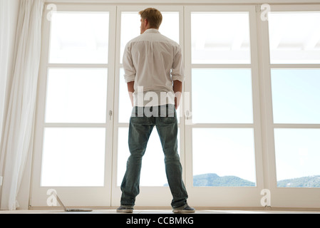 Man looking out window, rear view Stock Photo