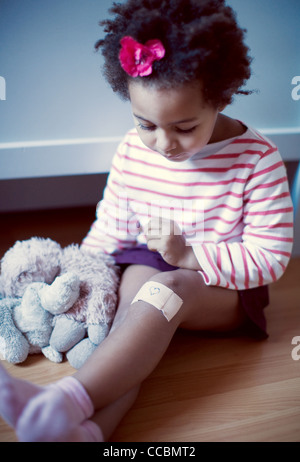 Little girl looking at adhesive bandage on knee Stock Photo