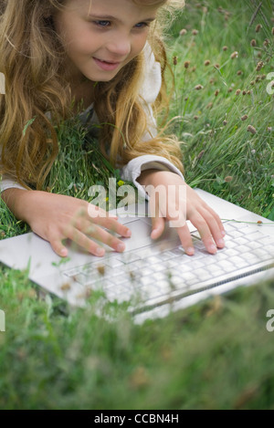 Girl lying in grass, using laptop computer Stock Photo