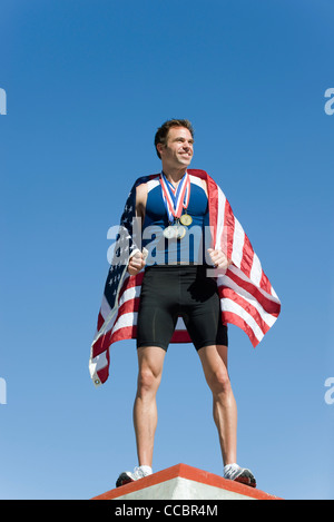 Male athlete on winner's podium, wrapped in American flag Stock Photo