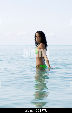 Young woman in bikini standing waist deep in water, portrait Stock Photo