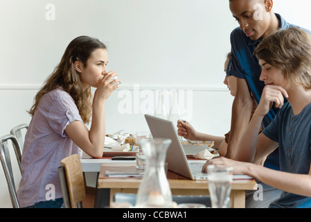 Friends in restaurant, woman dining, man using laptop computer Stock Photo