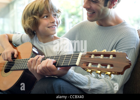 Boy learning how to play guitar with father Stock Photo