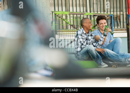 Friends sitting on sidewalk toasting Stock Photo