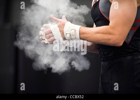 Gymnast applying chalk power to hands in preparation Stock Photo