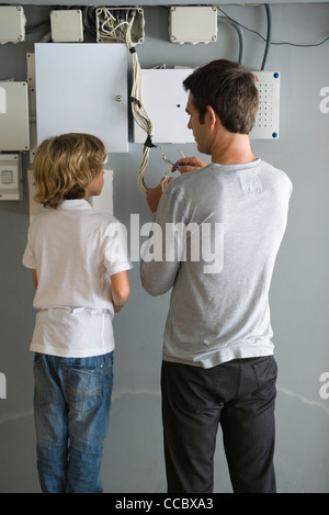 Son watching father fixing wires Stock Photo