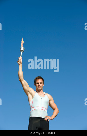 Male athlete holding up torch Stock Photo