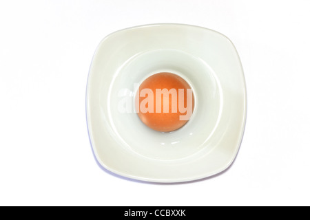 Brown egg in an egg cup in front of white background Stock Photo