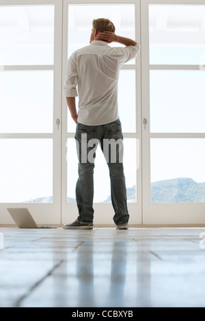 Man looking out window, rear view Stock Photo