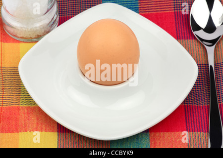 Breakfast egg in an egg cup with spoon and salt mill Stock Photo