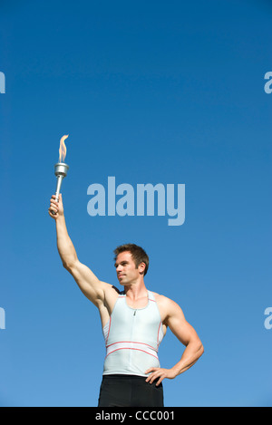 Male athlete holding up torch Stock Photo